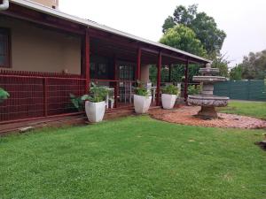 a porch of a house with three potted plants at Lily Guesthouse in Bloemfontein