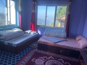 a room with a bed and a bench and windows at Aanshi homestay in Nagarkot