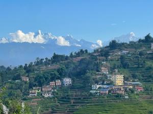 a village on a hill with mountains in the background at Aanshi homestay in Nagarkot
