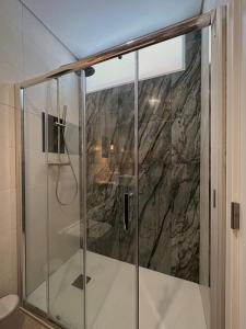 a shower in a bathroom with a marble wall at Casa dos Camilos - Douro View Terrace House in Peso da Régua +29 photos