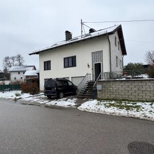 a black car parked in front of a white house at Danner Appartements Regau - Möblierte Langzeit- & Monteurapartments nahe Gmunden, Laakirchen, Salzburg & Wels I Vollmöbliert & mit Parkplatz in Rutzenmoos