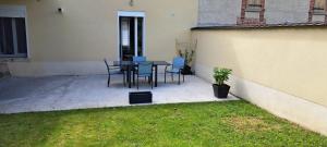 a patio with a table and chairs in a backyard at Maison Au 14 in Tours-sur-Marne