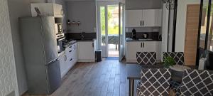 a kitchen with white cabinets and a refrigerator at Maison Au 14 in Tours-sur-Marne