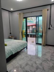 トランにあるเกาะลิบงKohlibong forest houseのベッドルーム1室(ベッド1台付)、ガラスのスライドドアが備わります。