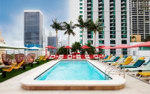 a swimming pool with chairs and umbrellas on a building at citizenM Miami World Center in Miami