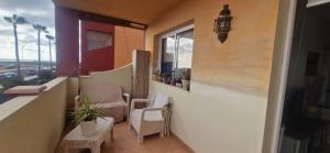 ein Balkon mit zwei Stühlen und einem Tisch und einem Fenster in der Unterkunft Marveo in La Oliva