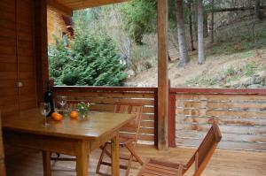a wooden table and chairs on a porch with a window at Котеджі Сім Вітрів in Volosyanka