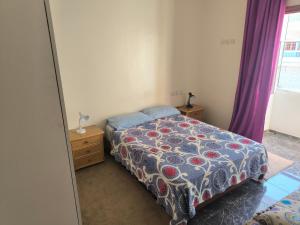 1 dormitorio con 1 cama y una ventana con cortinas moradas en Younes residence, en Asilah