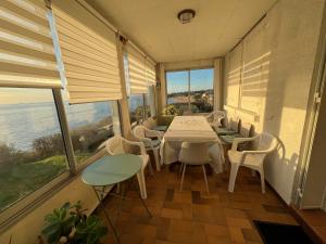 Un comedor con mesa y sillas y ventanas. en Maison face mer !, en Pornichet