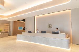 two people sitting at a reception desk in a lobby at 先泽酒店 in Huadu