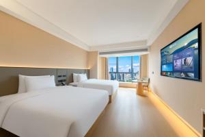 a hotel room with two beds and a flat screen tv at 先泽酒店 in Huadu +19 photos