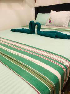 a bed with a green and white blanket on it at Ancient Tree in Mirissa