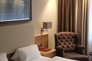 ein Hotelzimmer mit einem Bett, einem Stuhl und einem Fenster in der Unterkunft Hotel Brunnenhof International in Wedemark