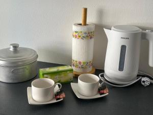 two cups on saucers on a counter with a coffee maker at Studio grande terrasse 2 min plage & commerces in Roquebrune-Cap-Martin