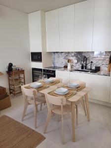 a kitchen with a wooden table and chairs with glasses on it at Villa Graça Olhão in Olhão