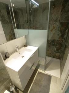 een badkamer met een witte wastafel en een douche bij Gite charles in Capbreton
