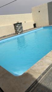 une piscine à l'eau bleue dans un immeuble dans l'établissement Villa agadir, à Glalcha