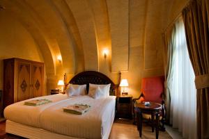 a bedroom with a large white bed and a table at CCR Cappadocia Cave Resort &Spa in Eskiömerler +74 photos