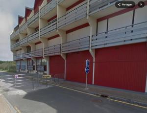 een rood-wit gebouw met een parkeerplaats bij Tamaris 26 in Quend-Plage