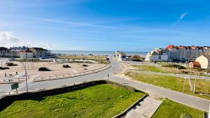 a road in a city with buildings and the ocean at Vue d'Opale - Appartement vue mer Stella-Plage in Stella-Plage
