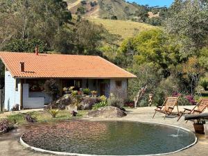 a small house with a pond in front of it at São João da Colina Ranch ItamonteMG in Itamonte