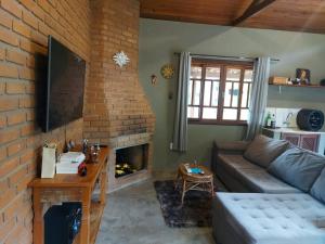a living room with a couch and a brick fireplace at São João da Colina Ranch ItamonteMG in Itamonte