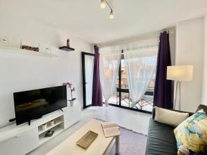 ein Wohnzimmer mit Sofa und Fernseher in der Unterkunft Hortensia Suites Apartments ,Los Cristianos in Los Cristianos