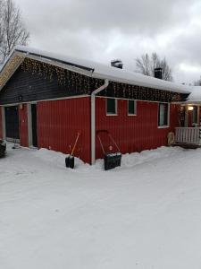 un granero rojo con nieve delante en Sulli apartment, en Rovaniemi