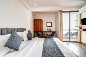 una camera da letto con un letto, una scrivania e una finestra di Hotel Breezy Heights Near IGI Delhi Airport by JIP a Nuova Delhi Altre 43 foto