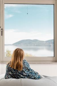 a woman sitting on a couch looking out a window at Kyveli Lake Suite in Kastoria