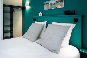 ein grünes Schlafzimmer mit einem Bett mit weißen Kissen in der Unterkunft Bread et Couette in Lyon