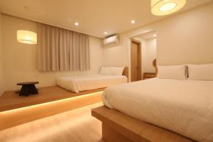 ein Hotelzimmer mit zwei Betten und einem Tisch in der Unterkunft 그리다 교동 in Tongdaegu-yŏk