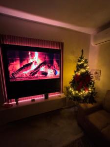 a christmas tree in a living room with a fireplace at Downtown Deluxe Apartment in Shkodër