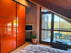 Un dormitorio con paredes naranjas y una gran ventana. en Asti Centro, Monferrato - Light Home with AC, Wifi, Park, Pool, en Asti