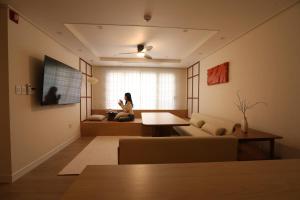 Eine Frau im Wohnzimmer mit Blick aus dem Fenster in der Unterkunft 그리다 교동 in Tongdaegu-yŏk