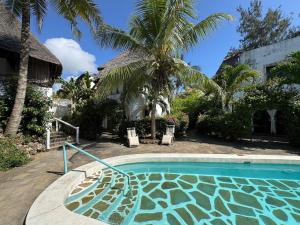 una piscina davanti a una casa con palme di Charming Cottage in Watamu a Watamu