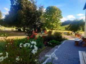 MühlthalFleischmannhof Do san ma dahoam的鲜花盛开的花园,砖砌的走道