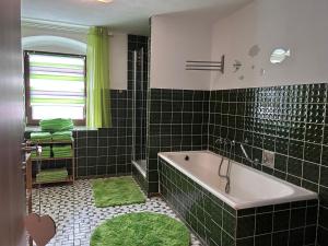 MühlthalFleischmannhof Do san ma dahoam的带浴缸和绿色瓷砖的浴室