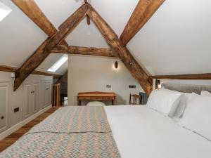 a bedroom with a large white bed and wooden beams at Walnut Cottage in Usk