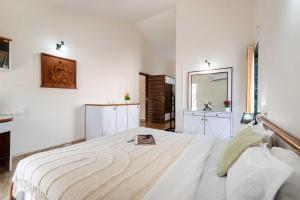 ein weißes Schlafzimmer mit einem Bett und einem Spiegel in der Unterkunft Villa Trizi by Palette Homes | 4BHK | Pvt Pool with Gazebo in Lonavla + 51 Fotos