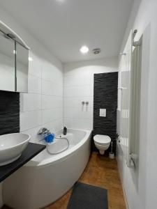 a bathroom with a tub and a sink and a toilet at Gemütliche Altbauwohnungen mit Einzelzimmern und Parkplatz direkt am Haus! in Bochum +15 photos
