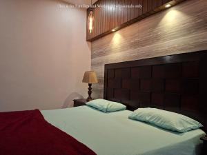 een slaapkamer met een groot bed met een houten hoofdeinde bij 2 Bedroom Serviced Home in Lahore