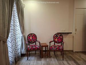 twee stoelen en een tafel voor een raam bij 2 Bedroom Serviced Home in Lahore +20 foto's