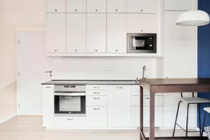 a kitchen with white cabinets and a wooden table at Flamingo Flat - Prague in Prague