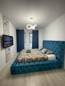 a bedroom with a blue tufted bed and a television at App Town North Pipera 23 in Voluntari