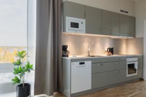 eine Küche mit weißen Schränken und einer Spüle und einem Fenster in der Unterkunft Forenom Aparthotel Luleå Västra Stranden in Luleå
