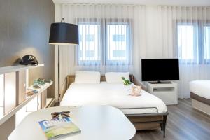 a hotel room with two beds and a flat screen tv at Novotel Suites Perpignan Centre - Grandes Suites & Confort Centre-Ville in Perpignan +98 photos
