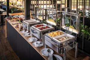 Una línea de buffet con varias bandejas de comida en New Port Aparthotel, en Cracovia