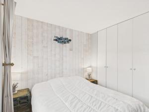 a bedroom with a white bed and a tiled wall at Au coeur du port, vue unique, appartement pour 6 in Saint-Martin-de-Ré