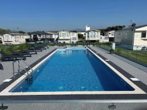 een zwembad met stoelen en huizen op de achtergrond bij Blue Skies in Llanwnda